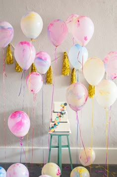 balloons and streamers are hanging from the ceiling in front of a wall with gold tassels