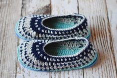 blue and white crocheted baby shoes sitting on top of a wooden floor next to each other