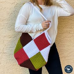 a woman is holding a crocheted handbag in front of a stucco wall