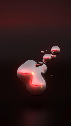 three drops of water with red light reflecting on the surface and one drop is falling off