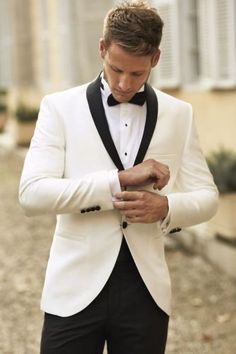 a man in a tuxedo looking down at his watch