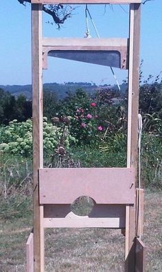 a wooden stand with a mirror on it in the middle of some grass and bushes