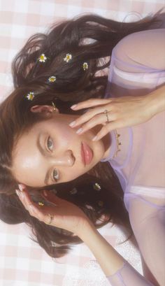 a woman laying on top of a bed next to a pink and white checkered blanket