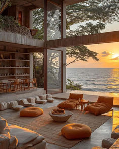 a living room with couches and chairs near the ocean at sunset or sunrise time