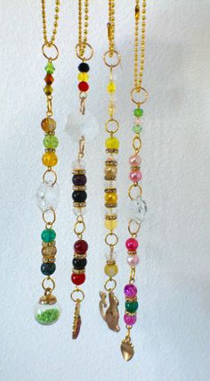 several necklaces hanging from hooks on a white wall with beads and charms attached to them