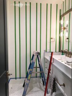 a bathroom with green and white stripes painted on the wall next to a step ladder