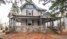 a gray house sitting on top of a dirt field