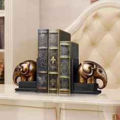 an elephant bookend sitting on top of a white table next to two bookshelves