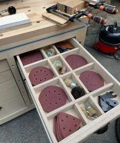 an open drawer with sanding discs and tools in it sitting on the floor next to a workbench