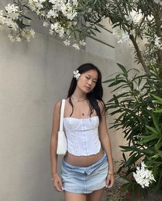 a woman standing next to a tree with white flowers in her hair and wearing a corset