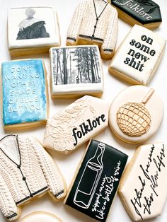 many decorated cookies are arranged on a white tablecloth with black and white writing in the middle