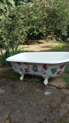 an old bathtub with flowers painted on the side and in front of some trees