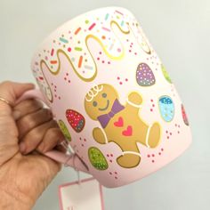 a hand holding up a pink cup with an image of a teddy bear on it