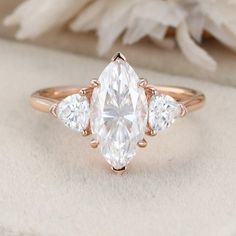 a three stone ring with two pear shaped diamonds on the side and an oval diamond in the middle