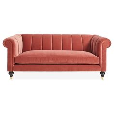 an orange velvet couch with wheels on the legs and armrests, in front of a white background