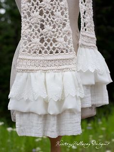 a white dress with ruffles and lace on the bottom is hanging from a mannequin