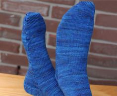 a pair of blue socks sitting on top of a wooden table next to a brick wall