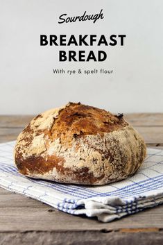 a loaf of bread sitting on top of a blue and white towel with the words sourdough breakfast bread