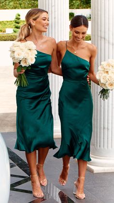 two bridesmaids in green dresses walking down the aisle holding bouquets and flowers