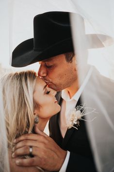 a bride and groom kissing under a veil