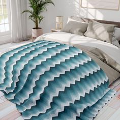 a bedroom with a large bed covered in a blue and white chevroned blanket