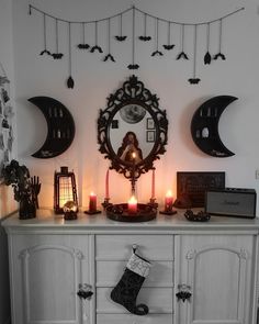 a white dresser topped with lots of candles next to a wall mounted clock and mirror