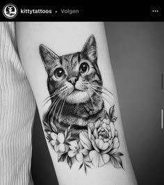 a black and white photo of a cat with flowers on it's arm,