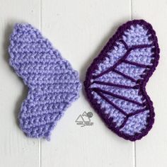 two crocheted leaves sitting on top of a white wooden table next to each other