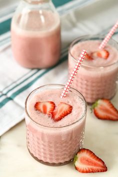 two glasses filled with strawberry milkshakes and strawberries