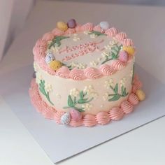 a pink and white decorated cake on top of a table next to a card board