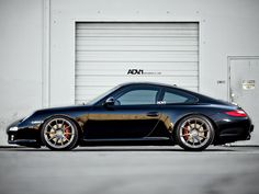 a black sports car parked in front of a garage door