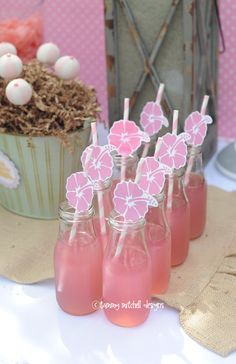 there are pink drinks in mason jars with strawberries on top and paper flowers sticking out of them