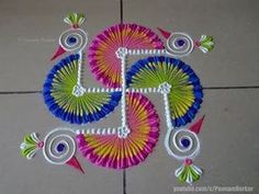 a colorful rangdi design on the floor with white and blue circles, green leaves and pink flowers