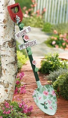 a garden tool leaning against a tree with flowers on it and the words welcome to my garden written on it