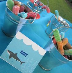 two buckets filled with gummy bears sitting on top of a blue table cloth