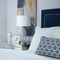 a bedroom with white bedding and blue headboard