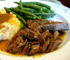 a white plate topped with meat, mashed potatoes and green beans