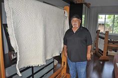 a man standing in front of a large white towel on a wooden rack next to a window