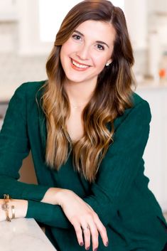 a woman sitting at a kitchen counter smiling for the camera