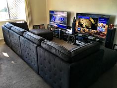 a living room filled with furniture and two flat screen tvs