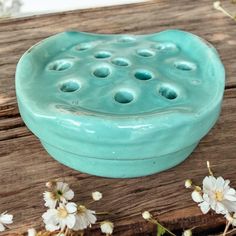 a blue ceramic bowl sitting on top of a wooden table next to flowers and daisies