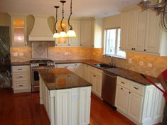 a kitchen with white cabinets and an island in the middle is being cleaned by a person