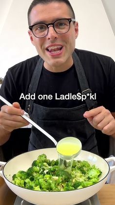 a man in an apron is holding a spoon over a bowl of broccoli