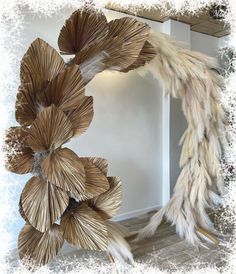 a sculpture made out of straw and feathers in a room with wood flooring on the walls