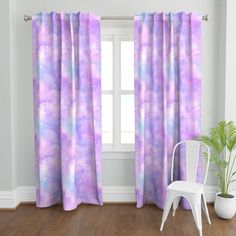 pink and blue tie dye curtains in a white room with a chair next to it