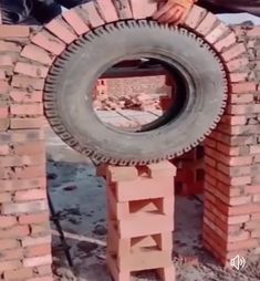 a person holding a large tire in front of a brick wall