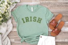 A simple & modern St Patricks Day graphic tee for women or men, perfect for celebrating the Irish holiday or giving as a St Patricks gift for a wife, sister or friend. Features a minimalistic green and yellow gold arched "IRISH" text design printed on our cozy heather sage green gender neutral crew neck tee. Made from quality, buttery-soft airlume cotton that provides all day comfort, breathability & durability. ☑ 52% airlume cotton + 48% polyester☑ Buttery-soft, light-weight & breathable materi Irish Tshirts, Lucky Shirt, Graphic Tops, Tees For Women, Text Design, Crew Neck Tee, Soft Light, St Patricks, Celebration Of Life