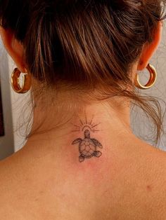 a woman with a turtle tattoo on her back neck and behind her ear is the sun