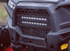 the front bumper and grille of an atv with its lights on, is seen in this close up photo