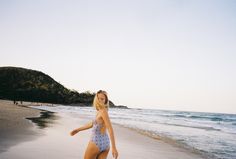 a woman in a bathing suit walking on the beach